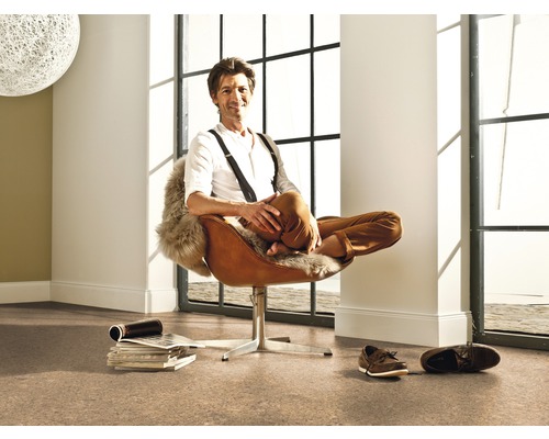 Cameră luminoasă cu podea de plută și bărbat în fotoliu maro