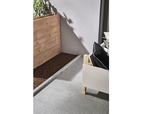 Scenă cu jardinieră din lemn, loc de stat și plăci de terasă gri.