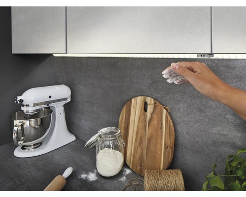 Scenă de bucătărie cu iluminare sub dulap, robot de bucătărie, tocător și ingrediente