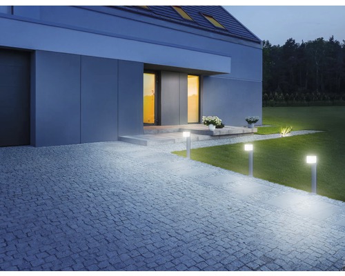 Spațiu exterior iluminat al unei case cu gazon și cărare de piatră