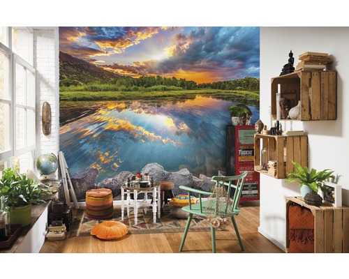 Cameră de zi cu fototapet cu un lac la apus, decorată cu diverse piese de mobilier și accesorii.