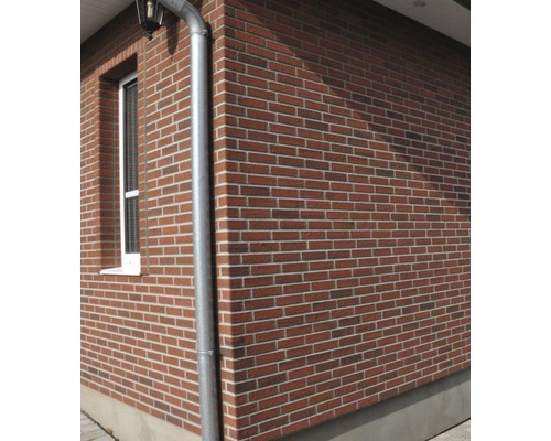 Exteriorul unei case cu fațadă din cărămidă și jgheab