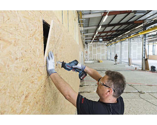 Un meseriaș taie o gaură într-o placă de lemn cu un ferăstrău sabie fără fir.