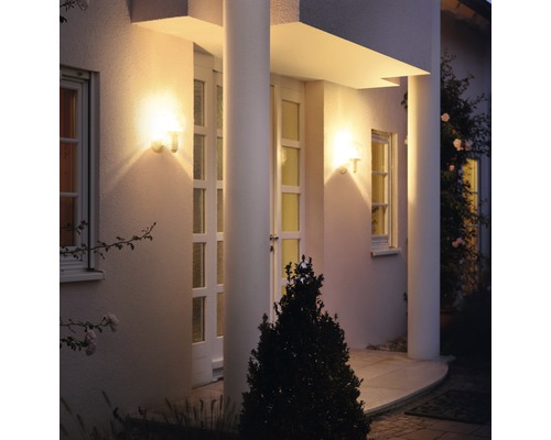 Fațadă de casă iluminată cu două corpuri de iluminat exterioare lângă o ușă