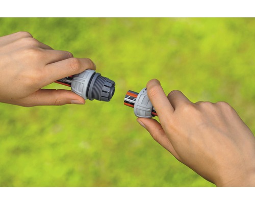 Două mâini conectează un racord de furtun la un furtun de grădină.