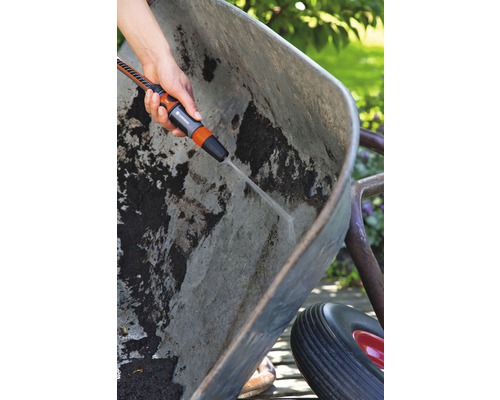 O persoană curăță o roabă murdară cu un pulverizator de grădină.