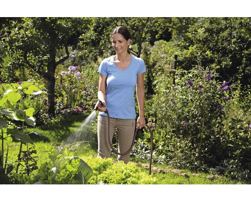 Femeie udând grădina cu furtun de grădină și pistol de pulverizare