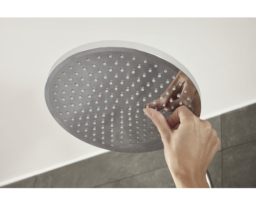 O mână curăță capul de duș cu funcție anticalcar.