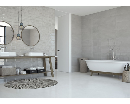 Baie modernă cu faianță gri, chiuvetă dublă și cadă de baie independentă.