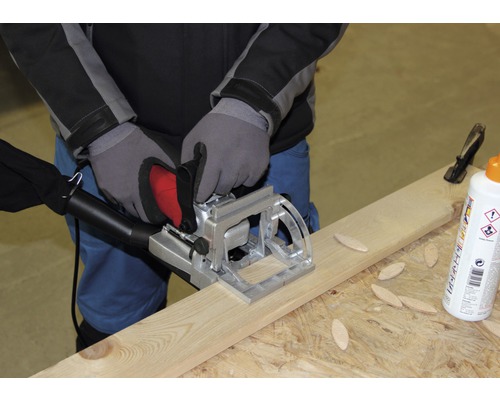 Un meșter folosește o freză de îmbinare pe o scândură de lemn, împreună cu conectori din lemn și adeziv.