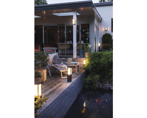 Terasa iluminată cu mobilier de grădină și iaz cu pești
