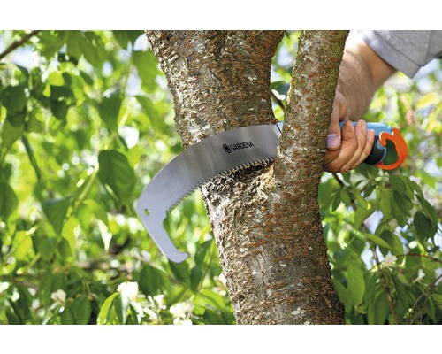 O persoană taie o ramură cu un fierăstrău manual marca Gardena.