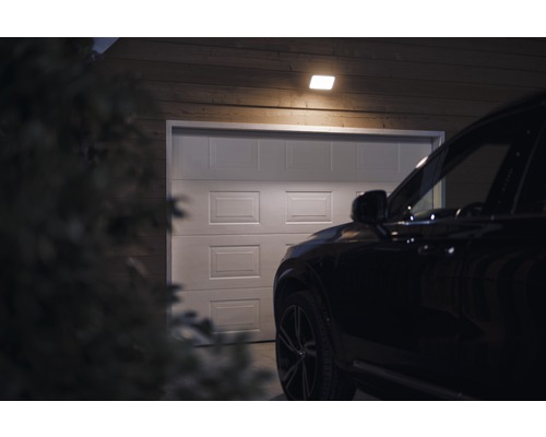 Scenă cu un garaj luminat de o plafonieră, cu o mașină în fața acestuia.