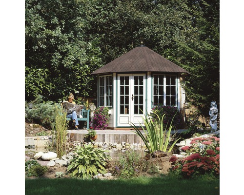 Foișor rotund cu ferestre și ușă într-un peisaj luxuriant de grădină cu iaz și persoană care citește