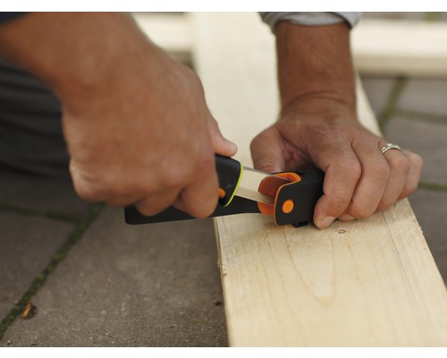 O persoană folosește o ascuțitoare pentru a ascuți un creion pe o scândură de lemn.