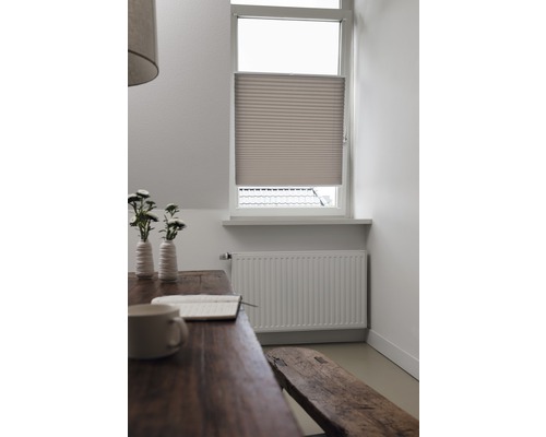 Scenă cu jaluzea plisată la fereastră, masă, bancă și calorifer