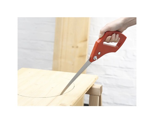 Un fierăstrău vertical cu mâner roșu taie o gaură într-o scândură de lemn.