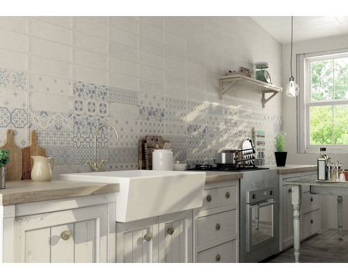 Bucătărie luminoasă cu perete de faianță în alb și modele albastre, chiuvetă și blat de lucru din lemn