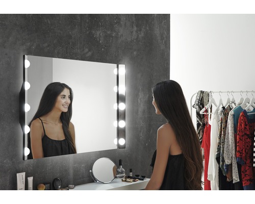 Femeie în fața unei oglinzi cosmetice iluminate în baie.