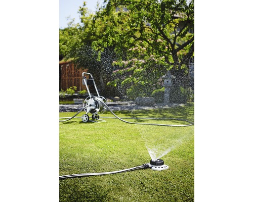 Scenă de grădină cu aspersor de gazon și cărucior pentru furtun pentru irigare