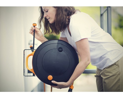 Femeie folosind cutia pentru furtun Fiskars pentru irigarea grădinii