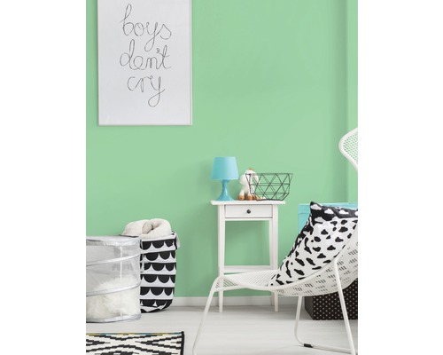 Cameră luminoasă cu vopsea de perete verde mentă, decorată cu scaun alb, noptieră și coș