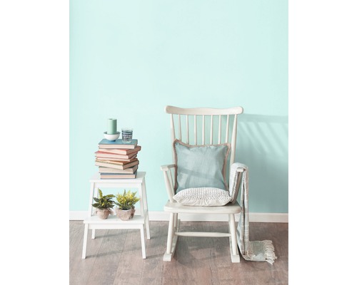 Scenă cu balansoar, măsuță laterală, cărți și decorațiuni într-o cameră luminoasă.