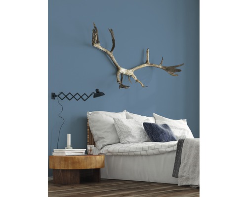 Dormitor cu pat, noptieră, lampă și coarne pe perete.