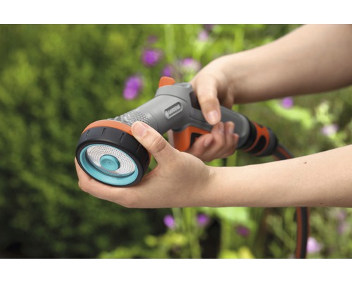 Persoană care ține în mână un pulverizator multifuncțional Gardena pentru irigare.