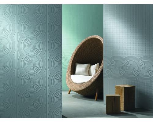 Scenă cu plăci de perete în relief cu design circular și un scaun din ratan cu perne.