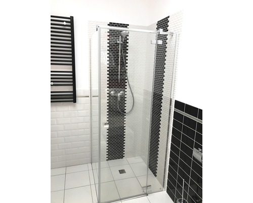 Cabină de duș walk-in cu perete de sticlă și calorifer negru în baie.