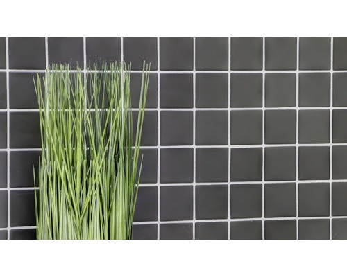 Plantă artificială decorativă în fața unui perete din plăci
