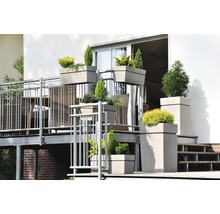 Scenă de balcon cu diverse jardiniere plantate de diferite dimensiuni și forme pe un balcon cu zonă de relaxare.