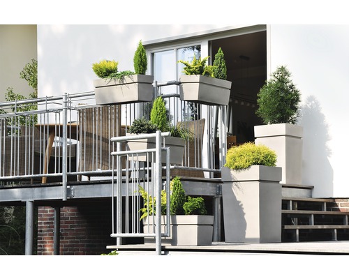 Scenă de balcon cu diverse jardiniere plantate de diferite dimensiuni și forme pe un balcon cu zonă de relaxare.