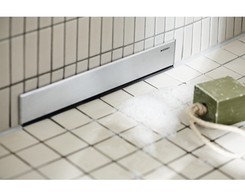 Canal de duș la nivelul podelei cu logo-ul Geberit în baie.