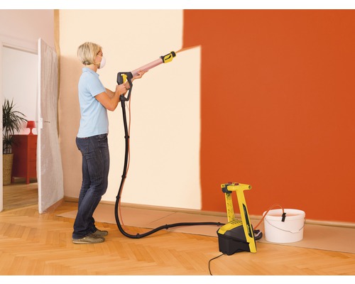 Femeie folosind un sistem de pulverizare a vopselei pentru a vopsi un perete