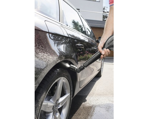 O persoană curăță o mașină cu un aparat de curățat cu presiune.