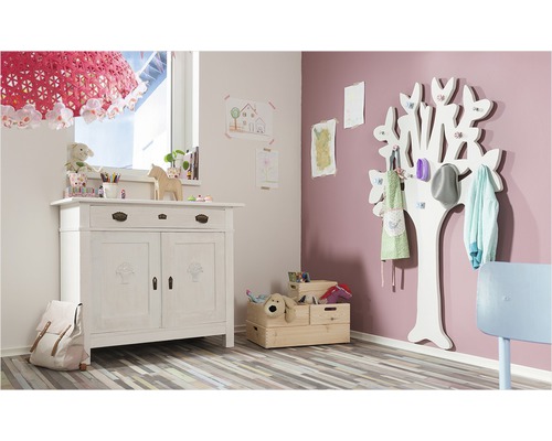 Cameră de copii cu comodă, dulap în formă de copac și cufere cu jucării.