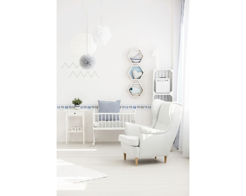 Cameră luminoasă pentru copii cu pătuț, fotoliu, măsuță laterală și decorațiuni de perete