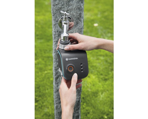 O persoană fixează un computer de irigare Gardena Smart Water Control la un robinet exterior.