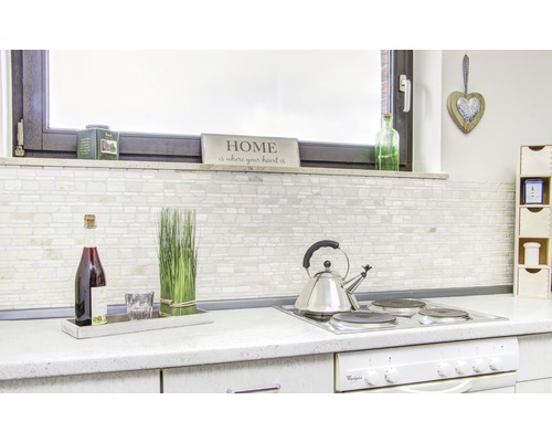 Bucătărie luminoasă cu perete cu gresie, băuturi și ustensile de bucătărie pe blatul de lucru