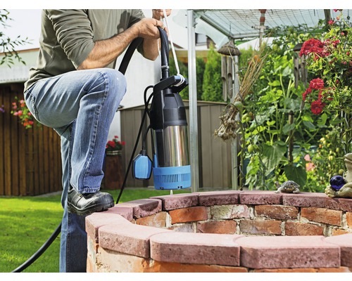 Bărbat cu pompă submersibilă într-o fântână de grădină