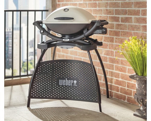 Grătar cu gaz Weber Q 1200 pe un balcon cu un zid de cărămidă în fundal.