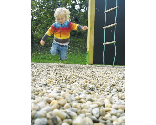 Un copil sare într-un loc de joacă lângă un zid de cățărare și o scară de frânghie.