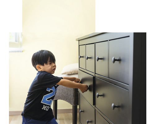 Copil care deschide sertarul unei comode cu mai multe sertare