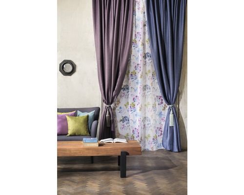 Cameră de zi cu canapea, masă din lemn și perdele în diferite culori și modele.