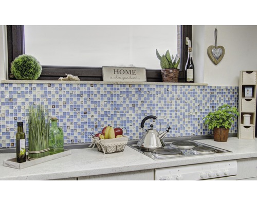 Scenă de bucătărie cu plăci de mozaic, decorațiuni și ustensile de gătit pe un blat de lucru.