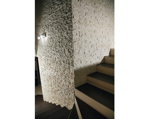 Fotografie de interior a unei scări lângă un perete cu decor de piatră