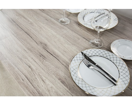 Masa de sufragerie cu veselă și tacâmuri pe un blat de masă cu aspect de lemn