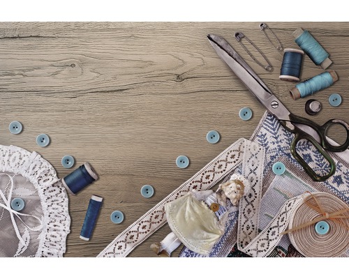 Scenă de cusut cu foarfece, nasturi, ață, ace de siguranță, dantelă și păpușă pe o masă de lemn